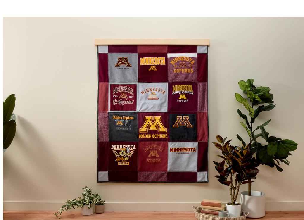 Quilt made from various Minnesota-themed t-shirts hanging on a wall.