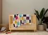 Wooden crib with a colorful patchwork memory quilt in a nursery setting.