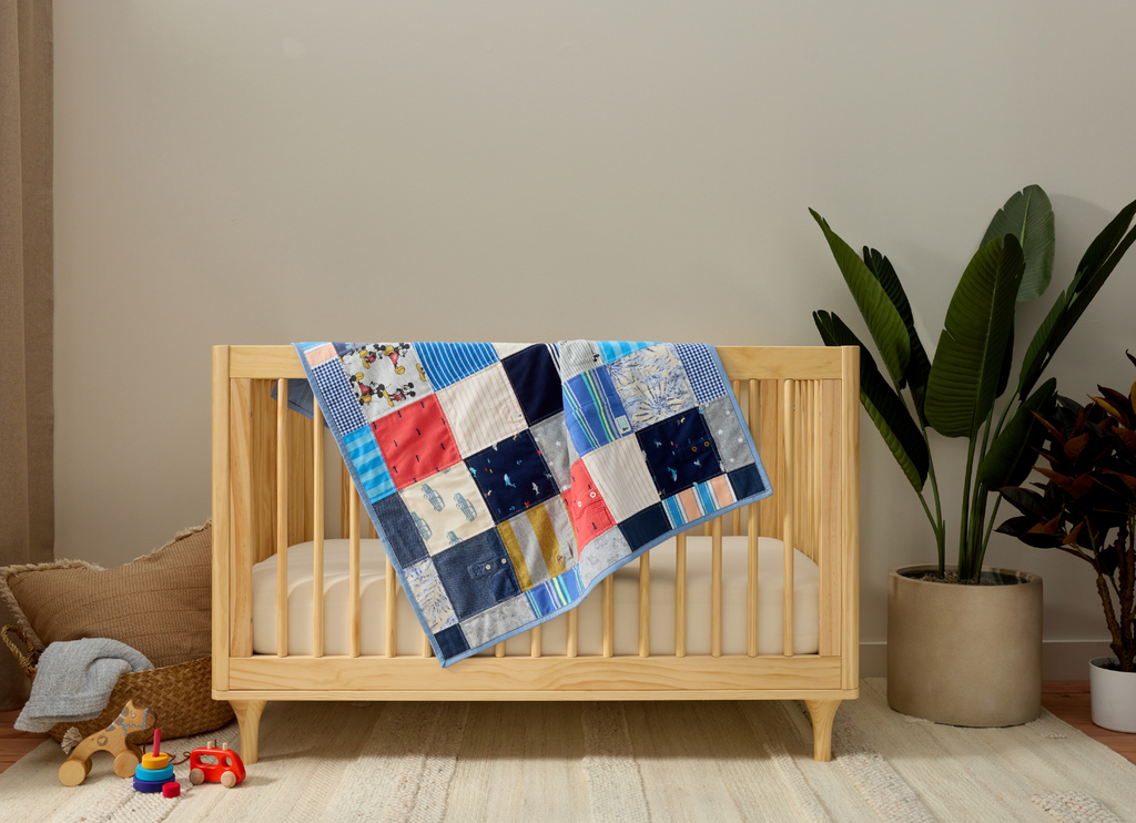Wooden crib with a colorful patchwork memory quilt in a room with plants and toys.